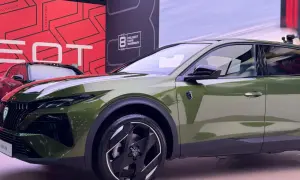 Nowy Peugeot 408 Hybrid w kolorze oliwkowym prezentuje się nowocześnie. Z przodu widoczny jest charakterystyczny grill i reflektory.