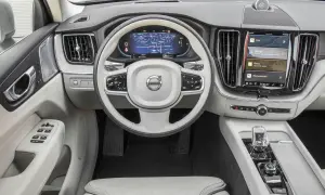Wnętrze Volvo XC60 T6 z ekranem nawigacji i multimediów. Jasna tapicerka, biała kierownica z logo Volvo.
