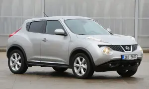 Srebrny Nissan Juke, często chwalony w nissan juke opinie, prezentuje się dynamicznie na tle nowoczesnej architektury.