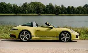 Żółty Porsche Targa z czarnym napisem na progu, zaparkowany nad jeziorem, otoczony zielenią.