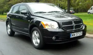 Czarny Dodge Caliber w ruchu, na mokrej drodze. Wiele osób szuka dodge caliber opinie, ten samochód wygląda na solidny.
