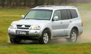 Srebrny Mitsubishi Pajero 3 pokonuje błotniste rozlewiska, unosząc chmury kurzu i wody.