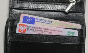 Czarny portfel z polskim dowodem osobistym i prawem jazdy. Na dokumencie prawa jazdy widnieje napis "PRAWO JAZDY" oraz symbol Unii Europejskiej.