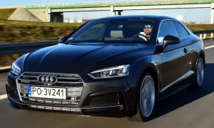 Czarny Audi A5 na drodze. Kierowca w okularach przeciwsłonecznych. Wiele osób chwali audi a5 opinie.