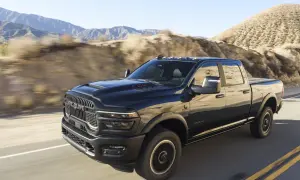 Czarny Dodge Ram 2500 pędzi po pustynnej drodze, góry w tle.