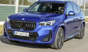 Niebieskie BMW X1 w ruchu, kierowca w okularach. Wiele osób szuka bmw x1 opinie przed zakupem.