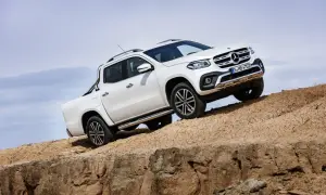 Biały mercedes pickup zjeżdża po piaszczystym zboczu, demonstrując swoje możliwości terenowe.