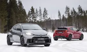Dwa sportowe toyoty hatchback GR Yaris na śniegu, jeden szary z przodu, drugi czerwony z tyłu, na tle zimowego lasu.