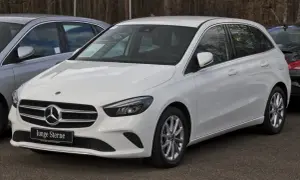 Biały mercedes hatchback z tabliczką "Junge Sterne" na grillu, gotowy do jazdy.