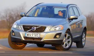 Srebrne Volvo XC60 z mężczyzną za kierownicą na drodze. Wiele osób szuka **volvo xc60 opinie** przed zakupem.