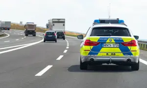 Niemieckie autostrady: radiowóz policyjny z włączonymi sygnałami świetlnymi jedzie za innymi pojazdami.