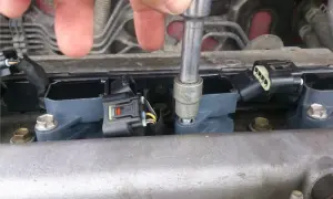Naprawa Opla z błędem dtc p0301. Mechanik dokręca cewkę zapłonową kluczem nasadowym.