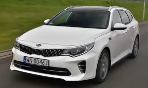 Biała Kia Optima w wersji kombi na drodze. Wiele pozytywnych kia optima opinie potwierdza jej wszechstronność.