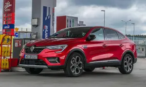 Czerwony Renault Arkana na stacji paliw. Wiele osób szuka **Renault Arkana opinie** przed zakupem.