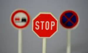 Trzy miniaturowe znaki drogowe: STOP, zakaz wyprzedzania i zakaz zatrzymywania się. Idealne do nauki przepisów ruchu drogowego.