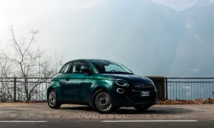 Zielony Fiat 500 na tle górskich krajobrazów. Wiele osób chwali ten model, a jego opinie są bardzo pozytywne.