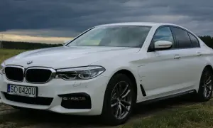 Białe BMW 530 na tle burzowego nieba. Elegancka limuzyna z polskimi tablicami rejestracyjnymi SC 0420U.