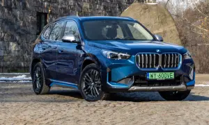 Błękitny BMW X1 elektryk z niebieskimi akcentami stoi na kamienistej drodze.
