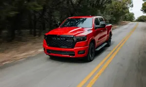 Czerwony Dodge Ram 1500 pędzi po krętej drodze wśród drzew.