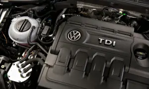 Silnik 2.0 TDI 140KM Volkswagena. Widoczny zbiornik płynu chłodniczego i osłona silnika z logo TDI.
