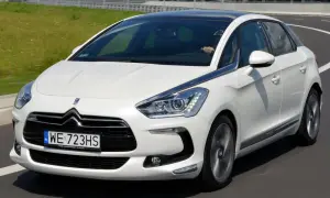 Biały Citroen DS5 na drodze. Kierowca za kierownicą. Wiele osób szuka pozytywnych **citroen ds5 opinie** przed zakupem.