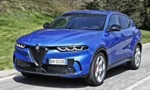 Niebieski SUV marki Alfa Romeo pędzi po asfaltowej drodze, otoczony zielenią.