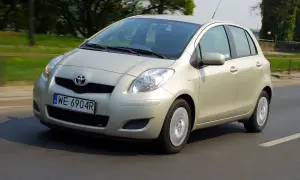 Złoty Toyota Yaris 2006 na drodze, z zielenią w tle.