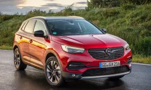 Czerwony Opel Grandland X na mokrej drodze. Wiele pozytywnych opinii o tym modelu.