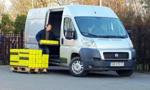 Mężczyzna rozładowuje żółte paczki z furgonetki Fiat Ducato 2.3.