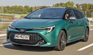 Zielona Toyota Corolla kombi jedzie po drodze, za nią widać drzewa i inny samochód.