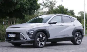 Nowe Hyundai Kona opinie: szary SUV z nowoczesnym designem, zaparkowany na bruku, otoczony zielenią.