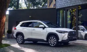 Biała Toyota Corolla Cross zaparkowana przed nowoczesnym budynkiem. Poznaj jej wymiary i możliwości.