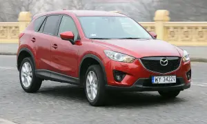 Czerwona Mazda CX-5 na drodze, z widocznym grillem i tablicą rejestracyjną.