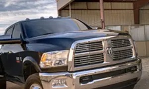 Ciemny Dodge Ram 3500 z chromowanym grillem i błyszczącym lakierem stoi przed budynkiem.