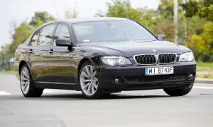Eleganckie czarne BMW 730d na polskich tablicach WI 8743F jedzie po drodze, otoczone zielenią.