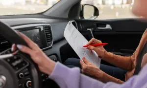 Wnętrze samochodu, kursantka wypełnia dokumenty. Sprawdza kurs prawo jazdy B cena.