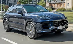 Ciemnoniebieski Porsche Cayenne w ruchu miejskim. Sprawdź aktualną porsche cayenne cena, aby poznać jego atrakcyjność.