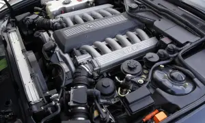 Silnik V12 BMW z widocznymi kolektorami dolotowymi i pokrywą z logo marki.