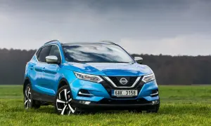 Niebieski Nissan Qashqai 1.6 benzyna na tle zielonej łąki i pochmurnego nieba.
