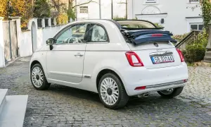 Biały fiat 500c cabrio z otwartym dachem stoi na brukowanej uliczce.
