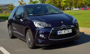 Granatowy Citroen DS3 w ruchu ulicznym. Kierowca w okularach przeciwsłonecznych. Wiele pozytywnych citroen ds3 opinie potwierdza jego styl.