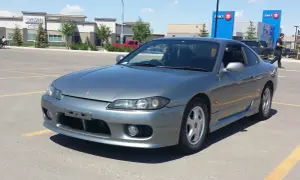 Szary Nissan Silvia s15 na parkingu przed budynkami BMO i Anytime Fitness.