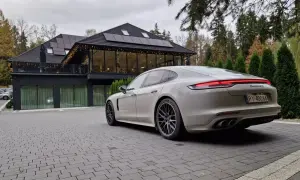 Białe Porsche Panamera GTS przed nowoczesnym budynkiem z panelami słonecznymi. Idealny wybór dla firm ceniących leasing operacyjny.