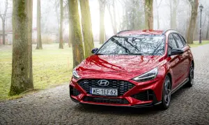 Czerwony Hyundai i30 Wagon N Line na kamienistej drodze w mglistym parku.