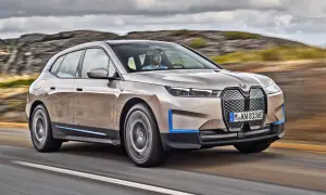 Elegancki suv BMW iX jedzie drogą wśród skalistych wzgórz.