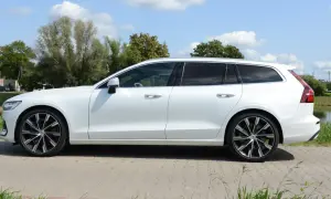 Białe Volvo T6 kombi stoi na tle zieleni i błękitnego nieba.