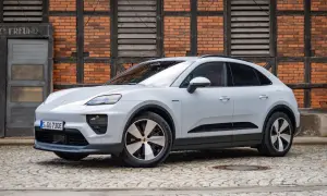 Biały Porsche Macan Electric na bruku, z ceglaną ścianą w tle. Sprawdź aktualną porsche macan cena.