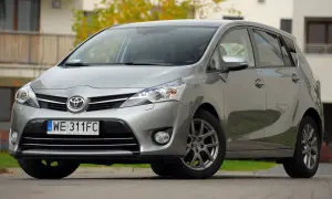 Srebrna Toyota Verso 1.8 benzyna zaparkowana przed budynkiem.