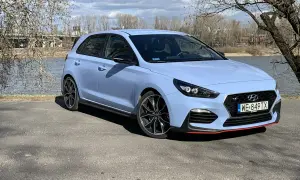 Niebieski Hyundai i30 N z czerwonymi akcentami stoi nad jeziorem, gotowy na wiosenną przejażdżkę.