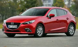Czerwona Mazda 3 2015 na parkingu, z widocznym numerem rejestracyjnym WY 3755W.